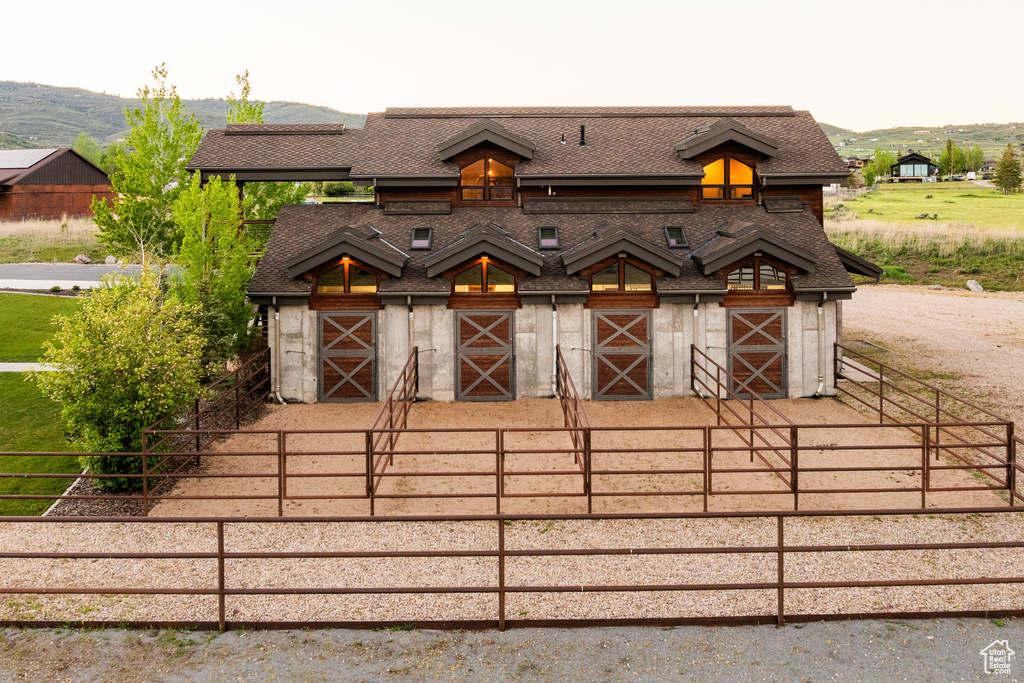 View of front of home with an exterior structure, an outdoor structure, roof with shingles, a mountain view, and a barn