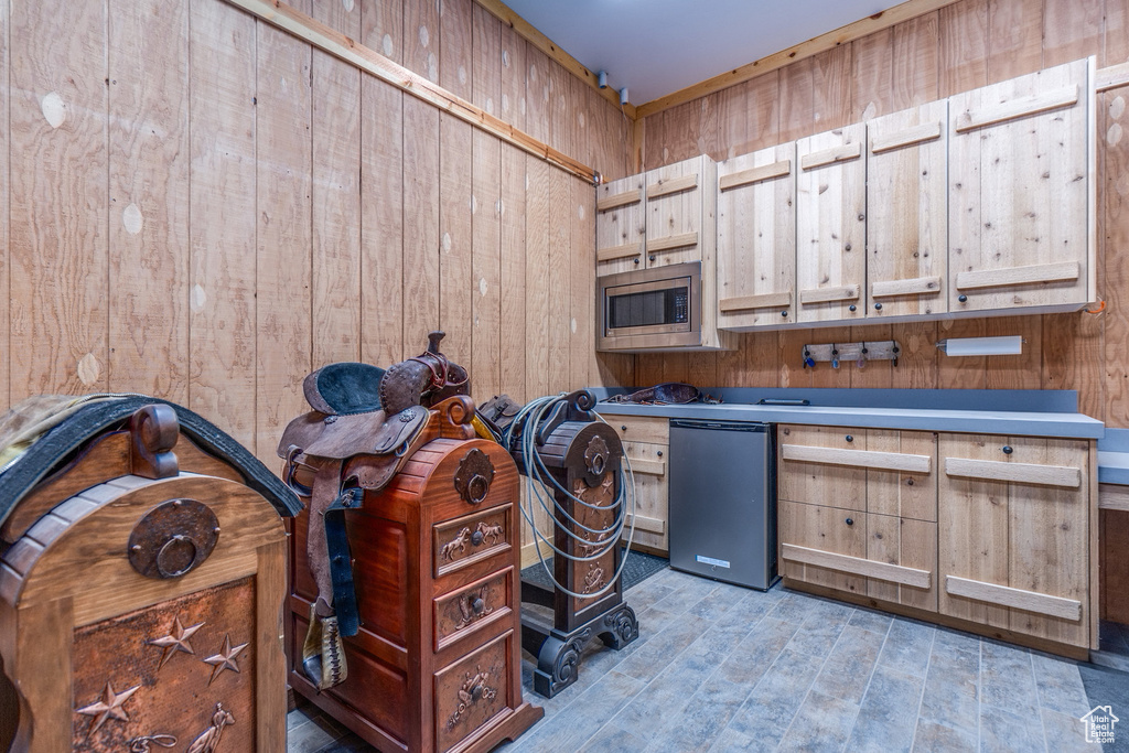 Kitchen featuring wood walls, stainless steel microwave, fridge, and wood finished floors