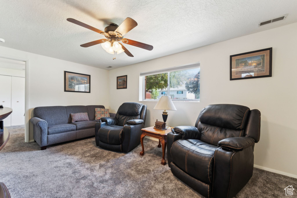 Living room with carpet floors, ceiling fan, and a textured ceiling