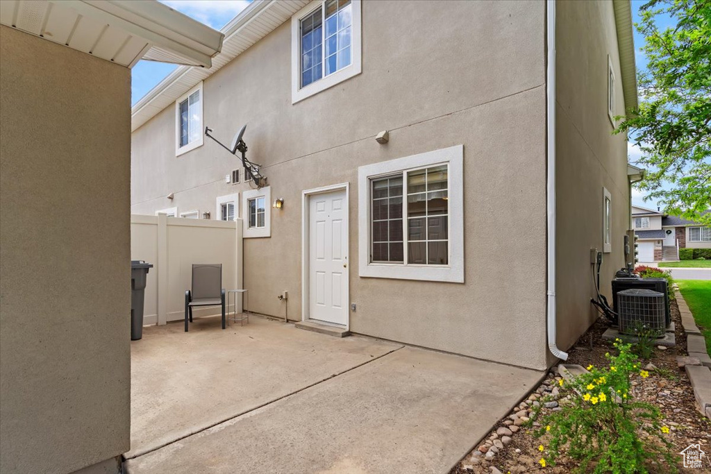 Rear view of house with a patio area, cooling unit, and stucco siding