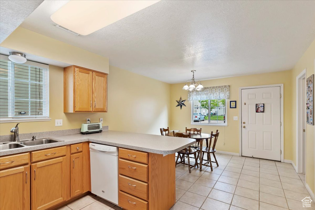 Kitchen with dishwasher, a peninsula, a sink, light tile patterned flooring, and a chandelier