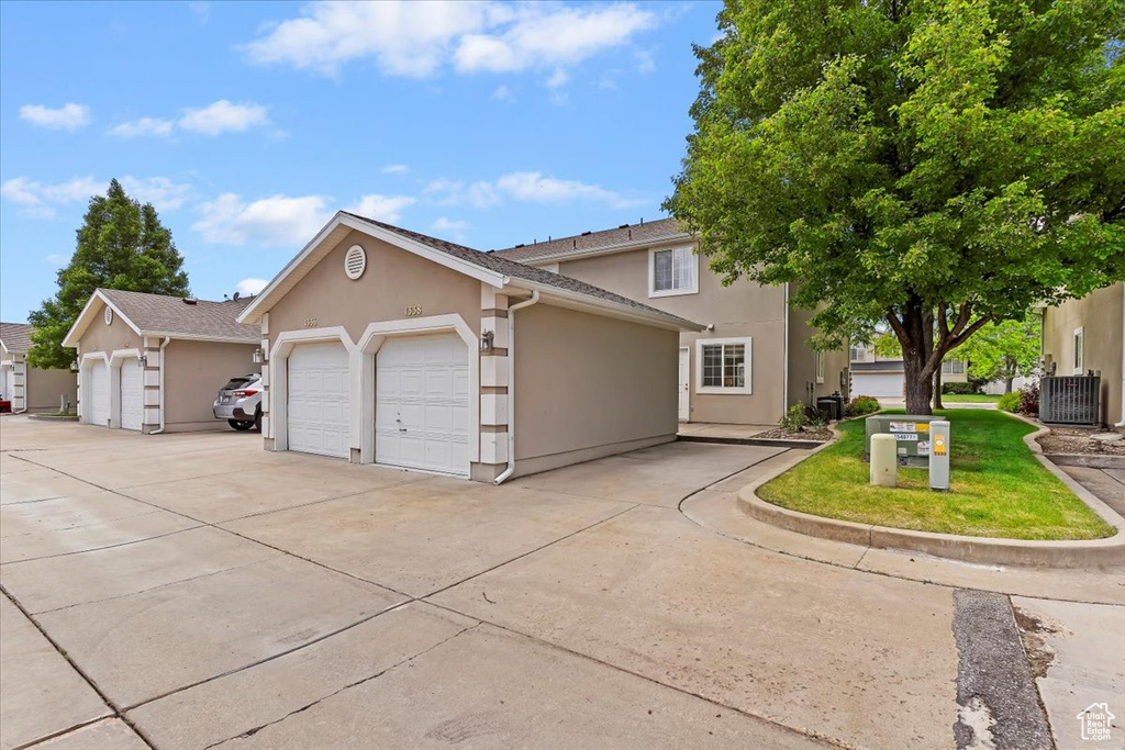 View of front of house with stucco siding, central AC, and an attached garage