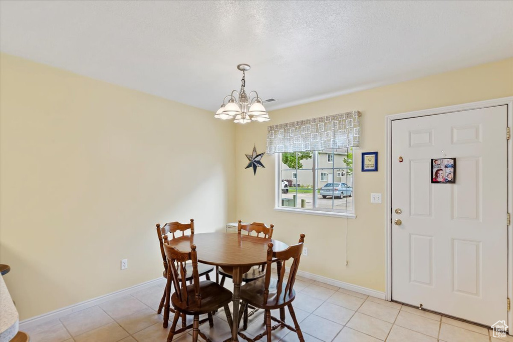 Dining room featuring a chandelier, light tile patterned floors, and baseboards