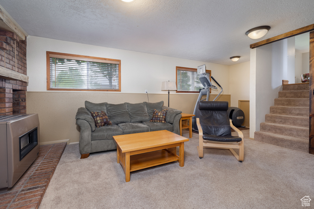 Carpeted living area featuring plenty of natural light, a textured ceiling, stairs, and a fireplace