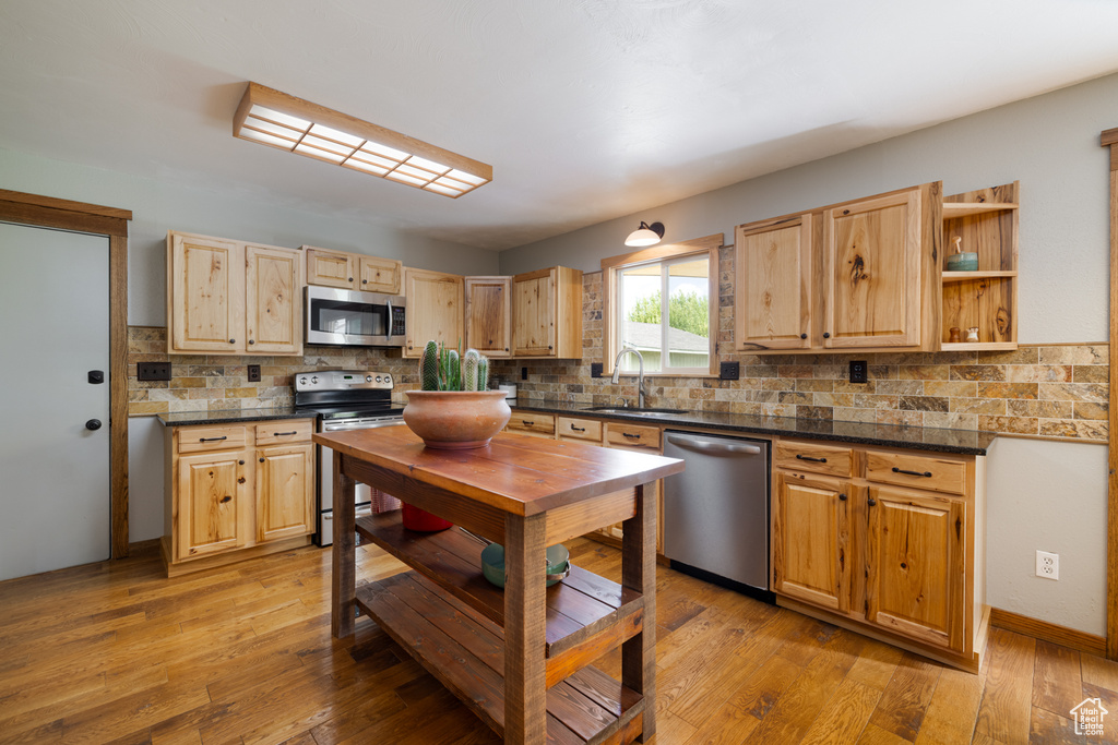 Kitchen with stainless steel appliances, a sink, dark countertops, and decorative backsplash