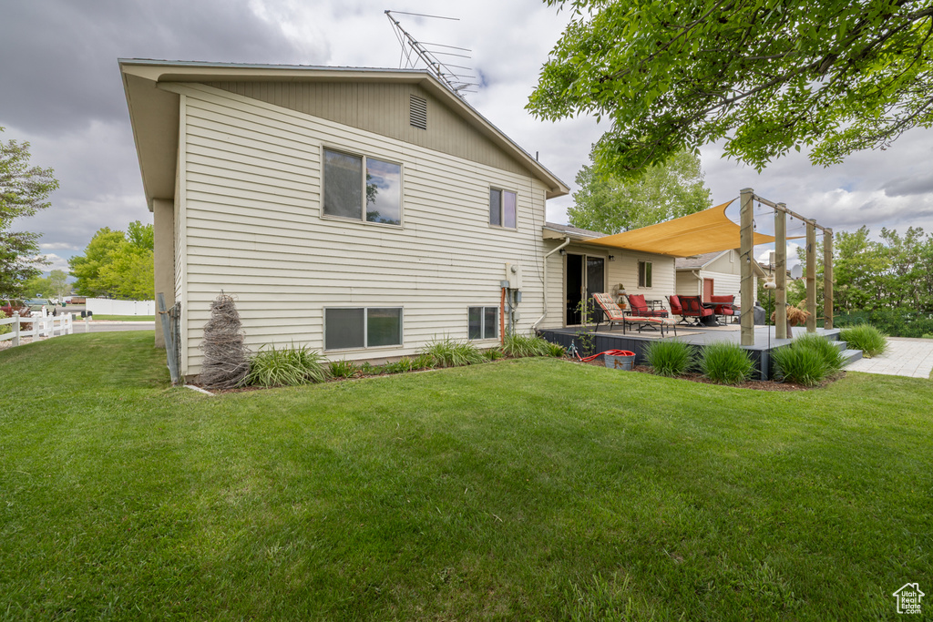 Rear view of property with a lawn and a patio