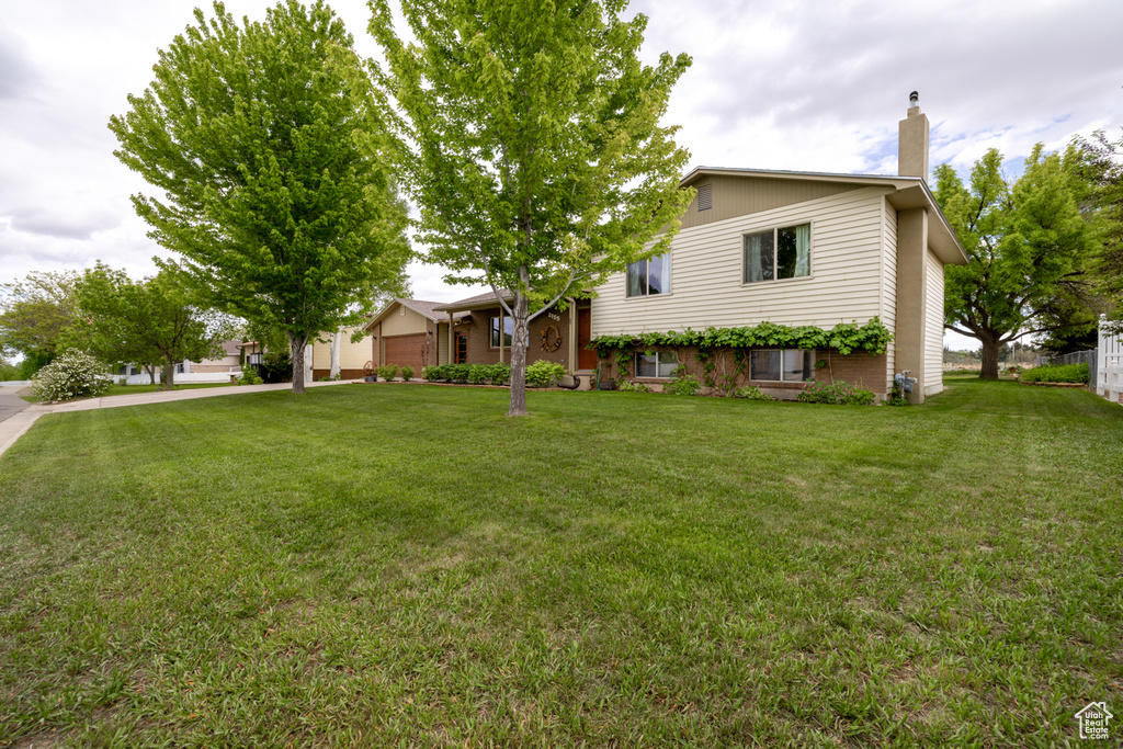 Tri-level home featuring a chimney and a front yard