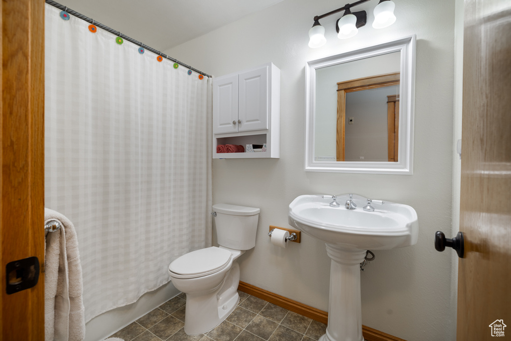 Bathroom featuring toilet, baseboards, and a shower with shower curtain