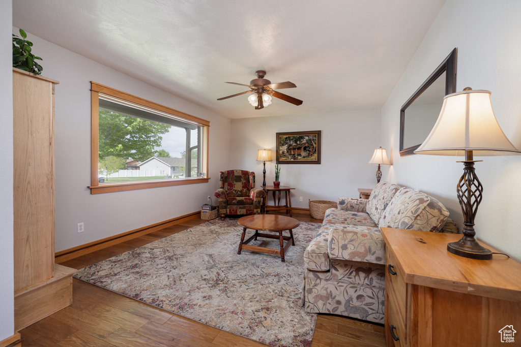 Living area with wood finished floors, a ceiling fan, and baseboards