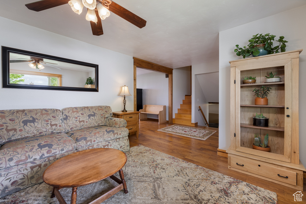 Living area featuring ceiling fan, wood finished floors, and stairs