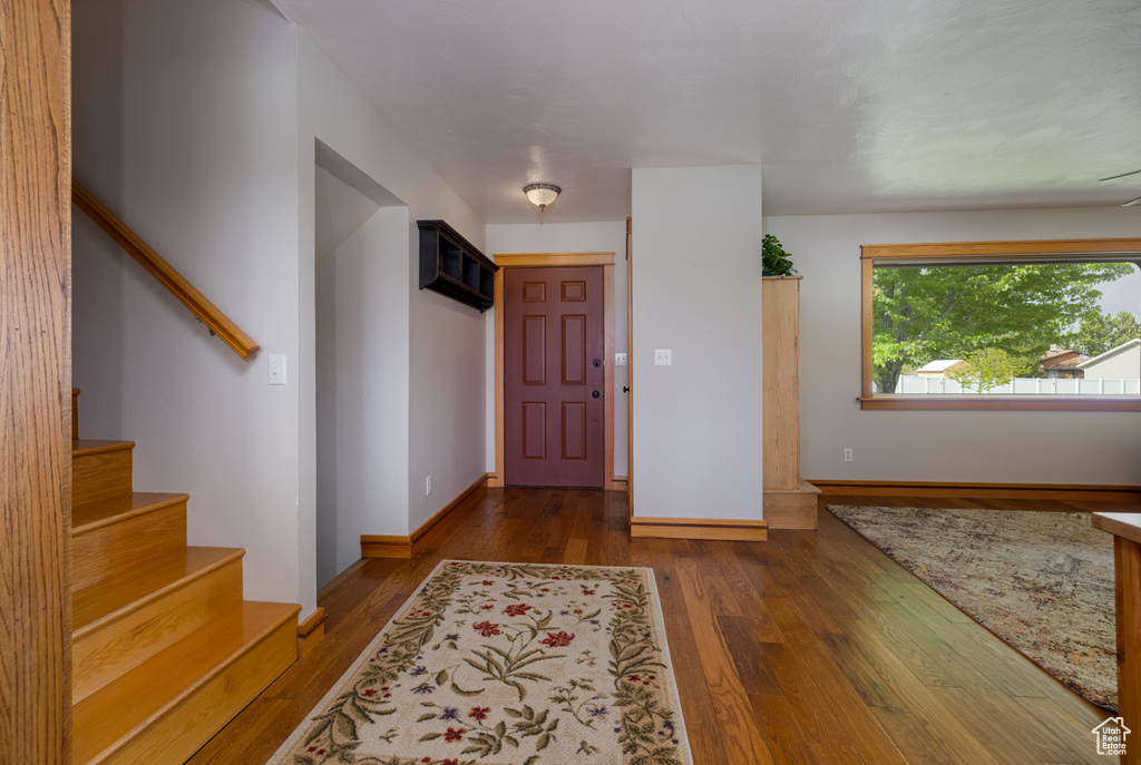 Foyer entrance featuring wood finished floors, stairway, and baseboards