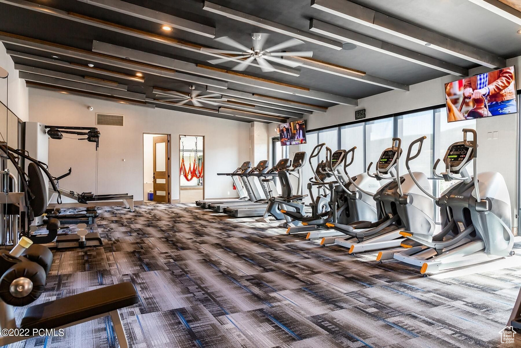 Workout area featuring carpet, plenty of natural light, ceiling fan, beam ceiling, and baseboards