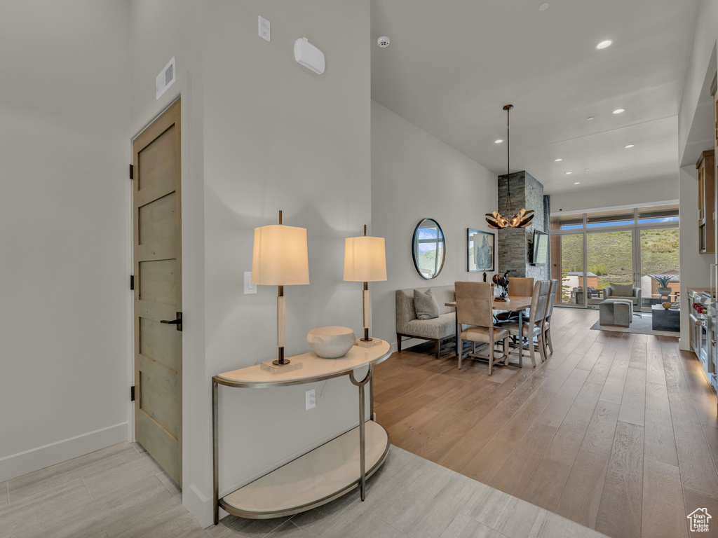 Living room with wood finished floors, a towering ceiling, recessed lighting, baseboards, and a chandelier