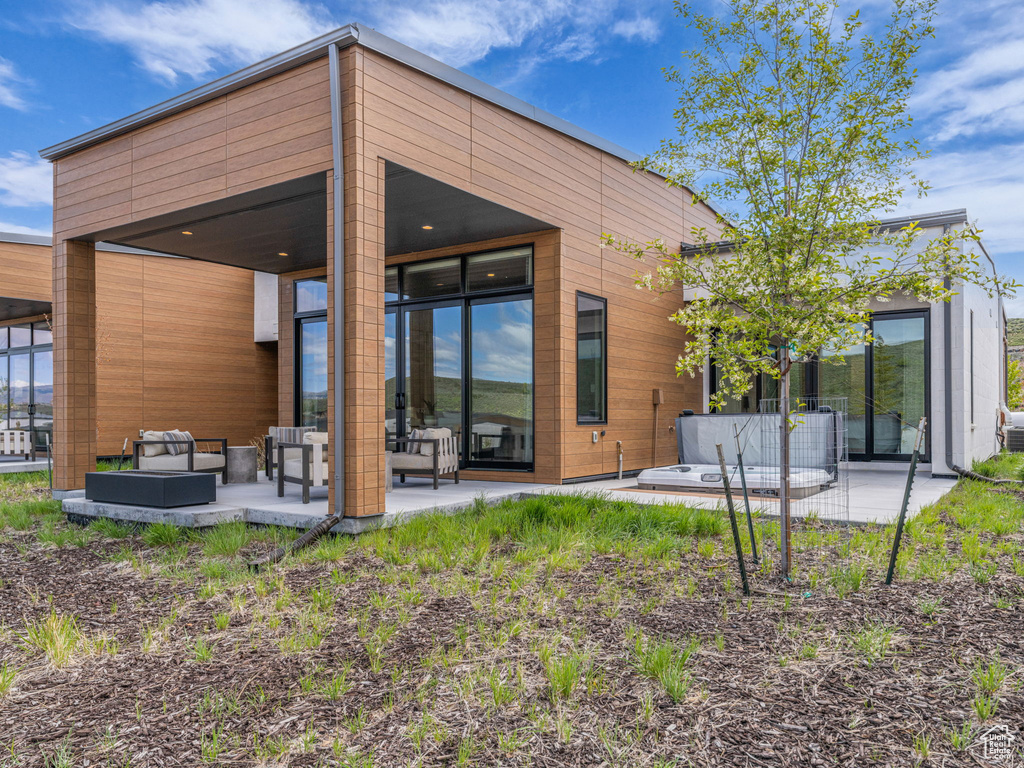 Rear view of property with an outdoor living space and a patio area