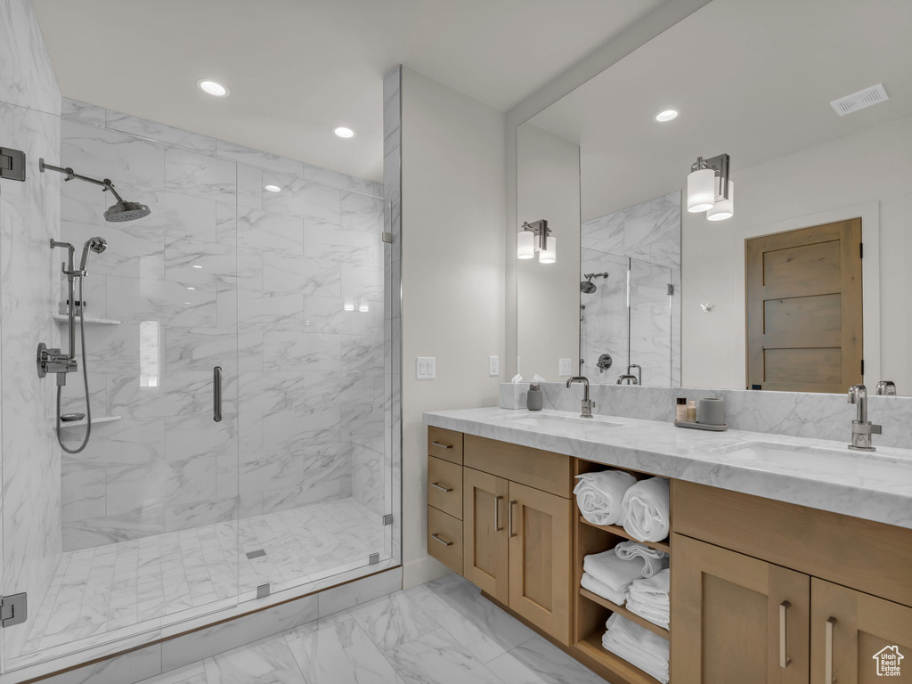 Full bathroom featuring marble look tiles, a marble finish shower, double vanity, and recessed lighting