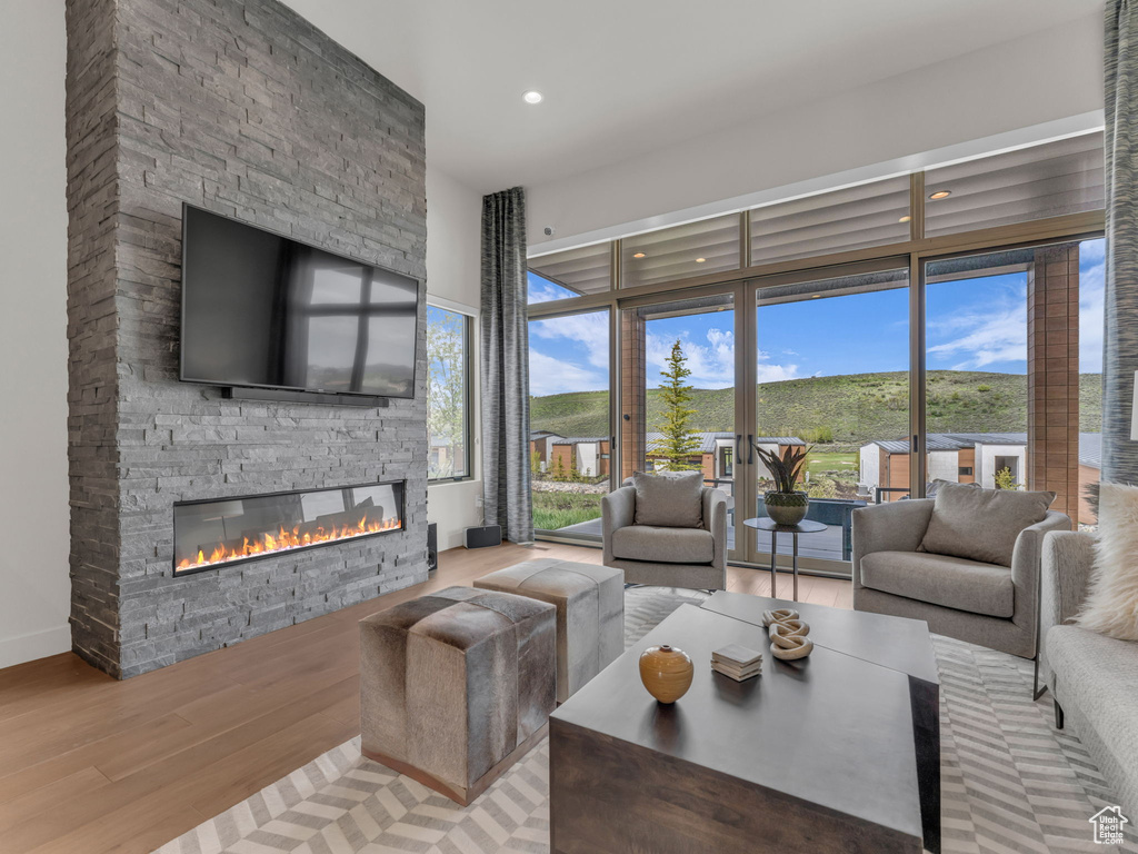 Living area featuring a stone fireplace, wood finished floors, recessed lighting, healthy amount of natural light, and baseboards