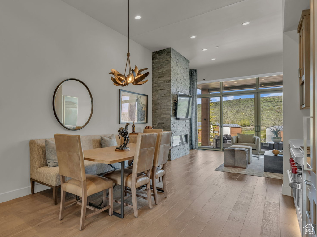 Dining room with light wood-style floors, a towering ceiling, a chandelier, recessed lighting, and baseboards