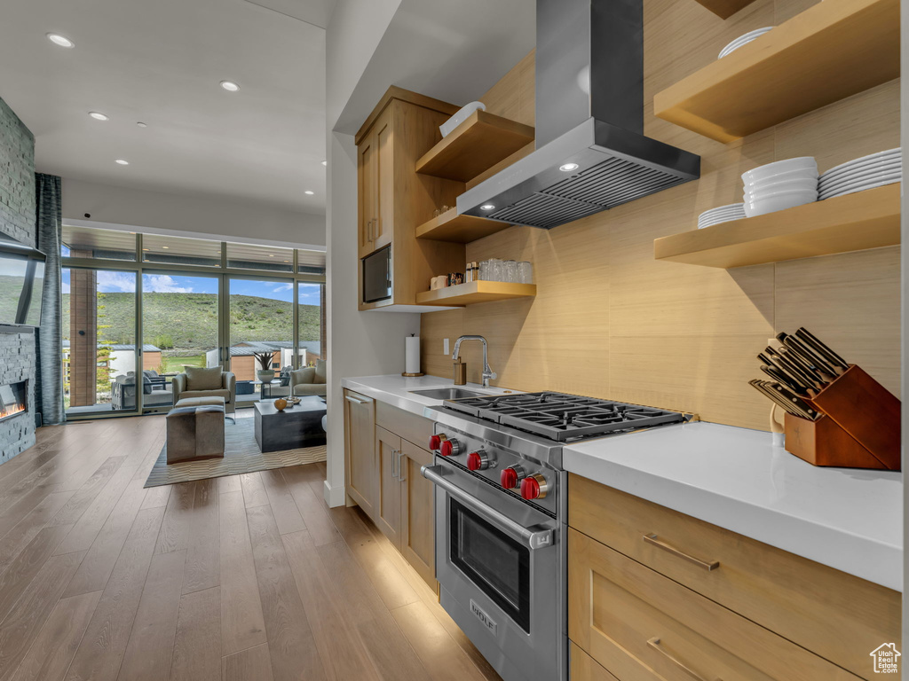 Kitchen with open shelves, designer stove, a sink, island exhaust hood, and backsplash
