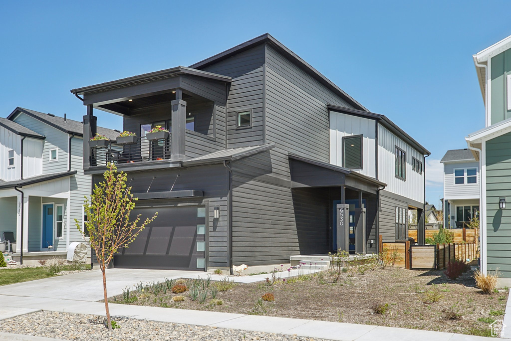 View of front of house with a garage, a balcony, and concrete driveway