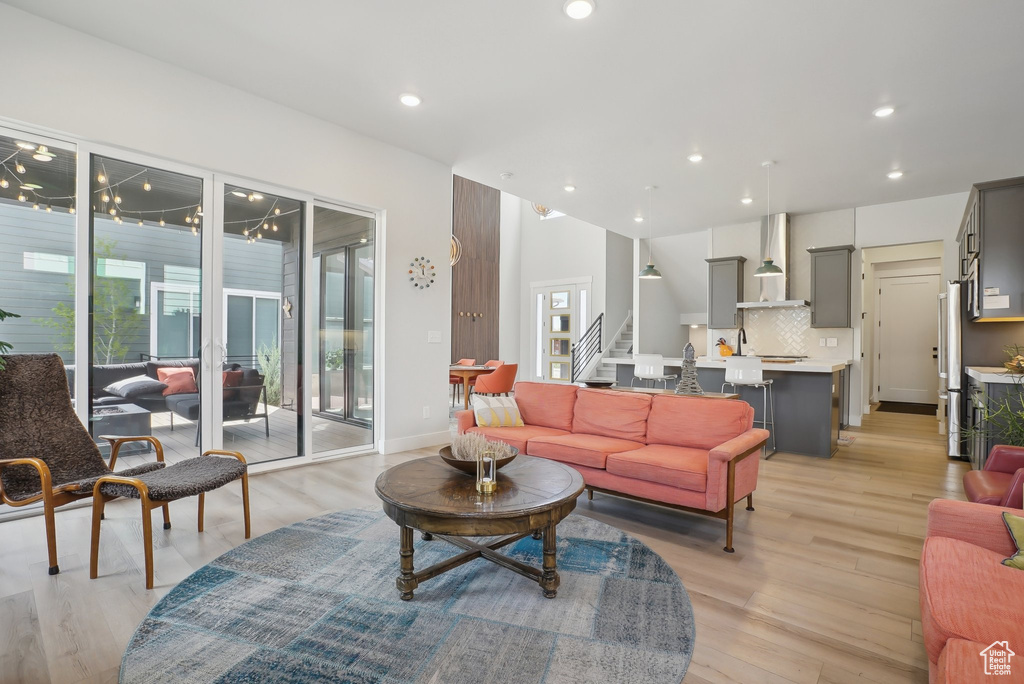 Living room featuring stairs, light wood-style floors, recessed lighting, and baseboards
