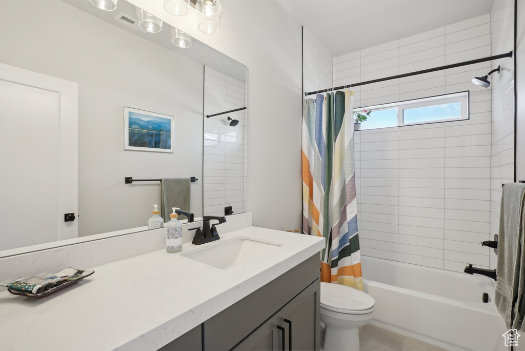 Full bathroom with vanity, shower / bath combo with shower curtain, and toilet