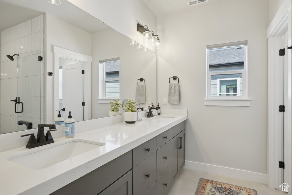 Bathroom with double vanity, a shower stall, baseboards, and tile patterned flooring