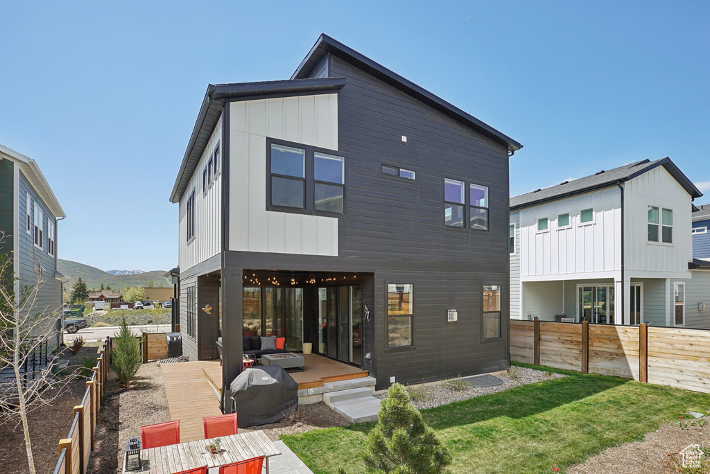 Rear view of house with a fenced backyard, board and batten siding, a mountain view, and a patio