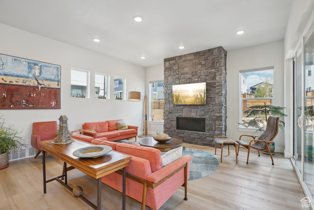 Living area featuring a stone fireplace, healthy amount of natural light, light wood-type flooring, and recessed lighting