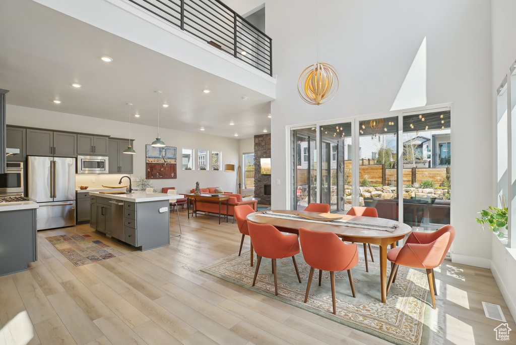Dining space featuring light wood-type flooring, a high ceiling, and recessed lighting
