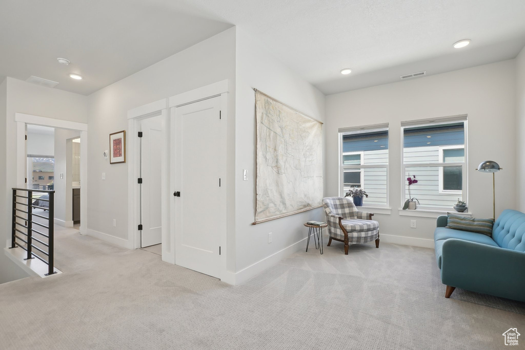 Living area with carpet, baseboards, an upstairs landing, and recessed lighting