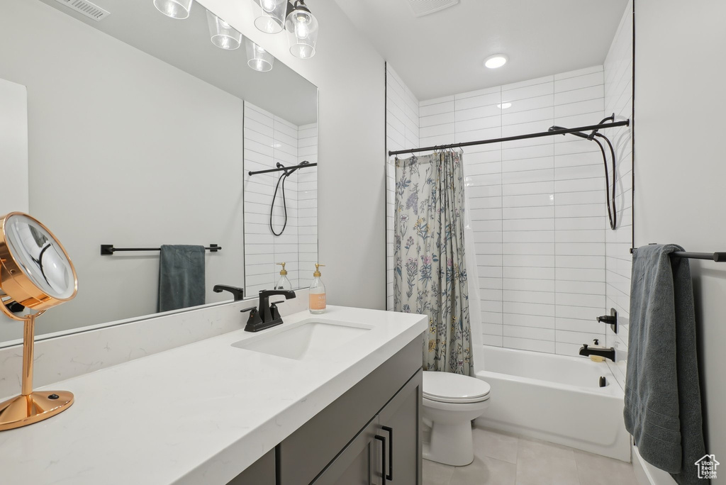 Bathroom featuring vanity, tile patterned flooring, shower / tub combo with curtain, and toilet