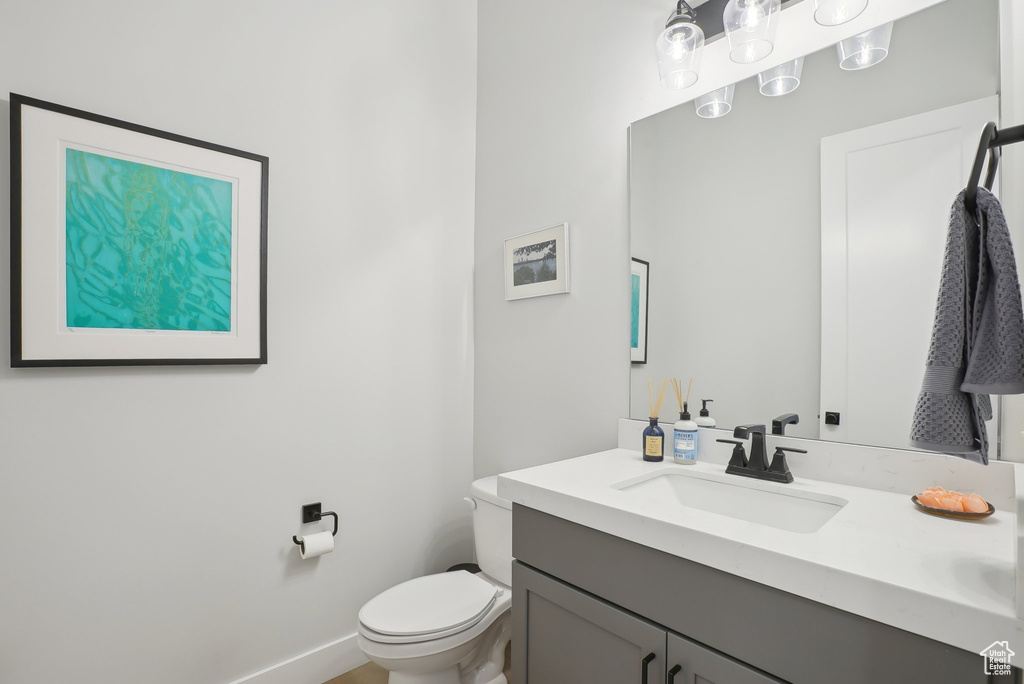 Half bathroom with toilet, vanity, and baseboards
