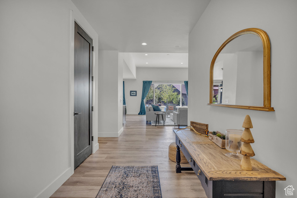 Hallway with light wood finished floors, baseboards, and recessed lighting