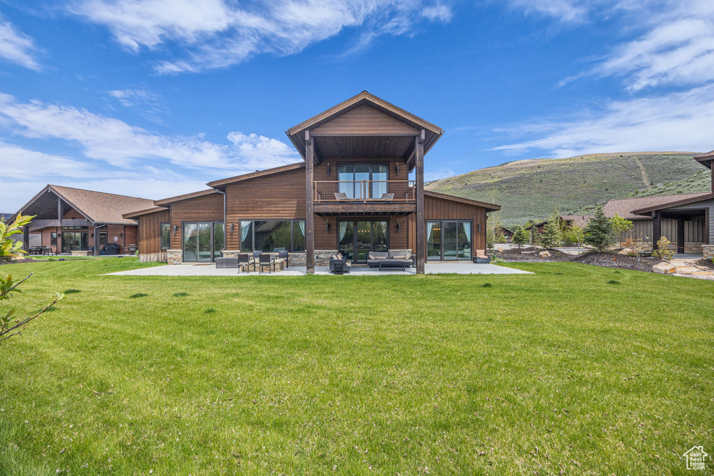 Back of house featuring a balcony, a patio area, an outdoor hangout area, and a yard