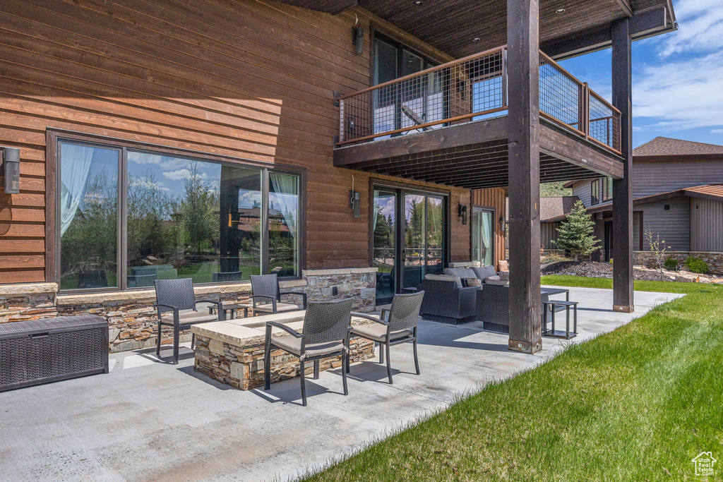 View of patio / terrace featuring an outdoor living space with a fire pit and a balcony