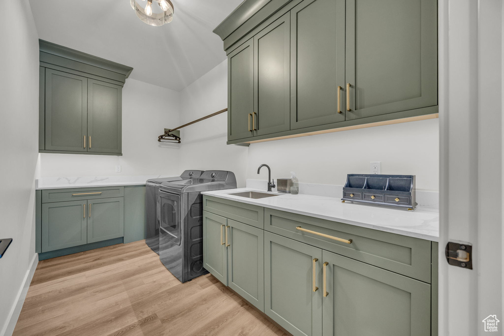 Laundry area with cabinet space, washing machine and dryer, and light wood-style flooring