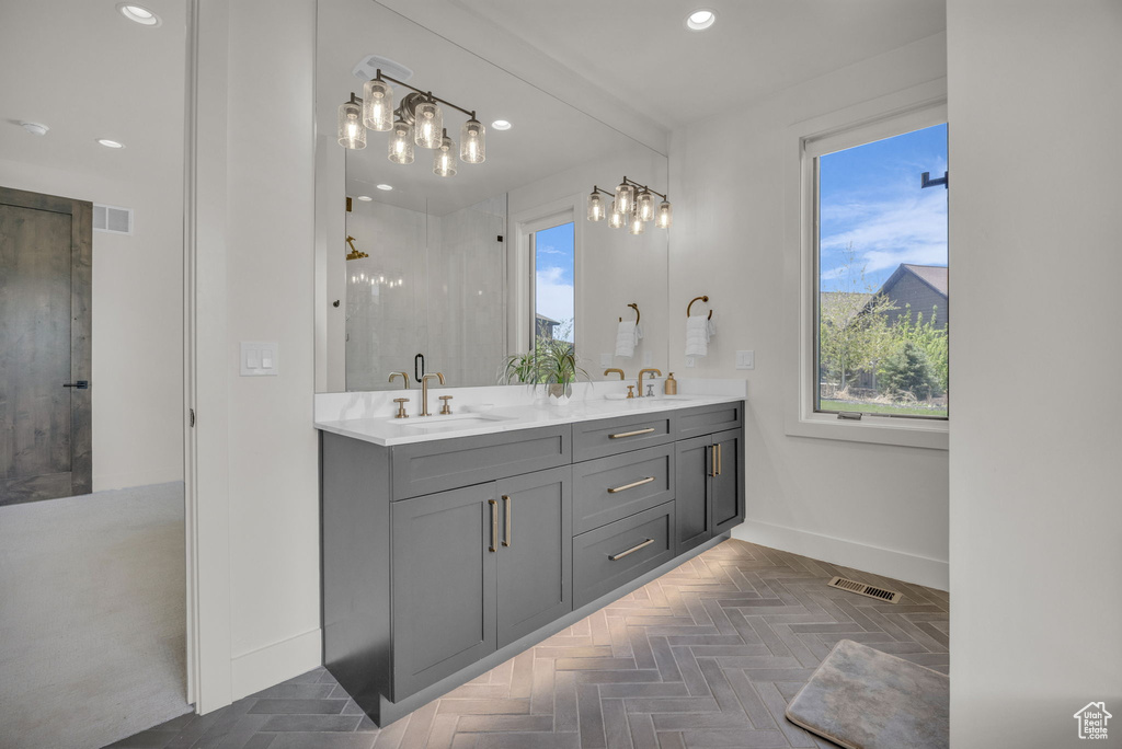 Full bath featuring baseboards, plenty of natural light, double vanity, recessed lighting, and a shower