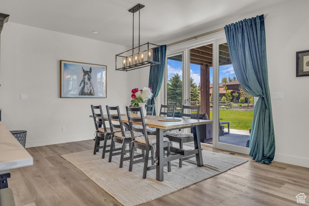 Dining room featuring baseboards, wood finished floors, and a chandelier
