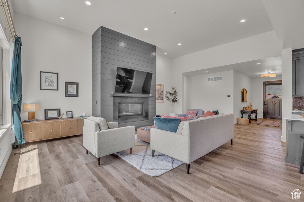 Living area with light wood-style floors, recessed lighting, and a large fireplace