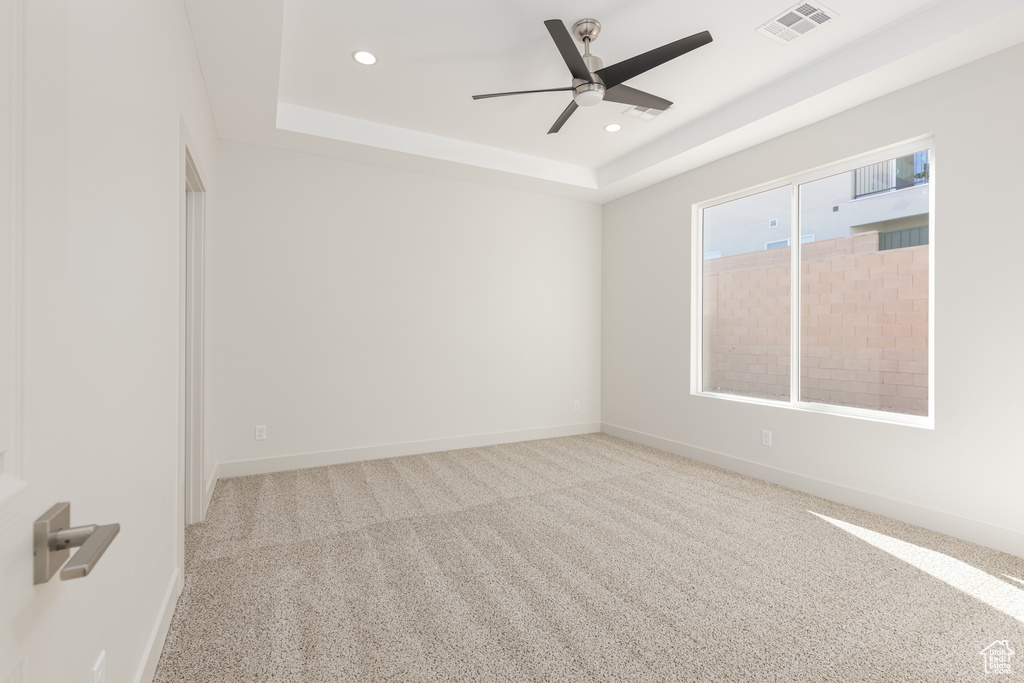Empty room with a raised ceiling, recessed lighting, a ceiling fan, baseboards, and carpet floors