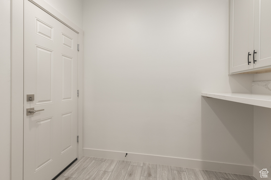 Doorway with baseboards and light wood-style flooring