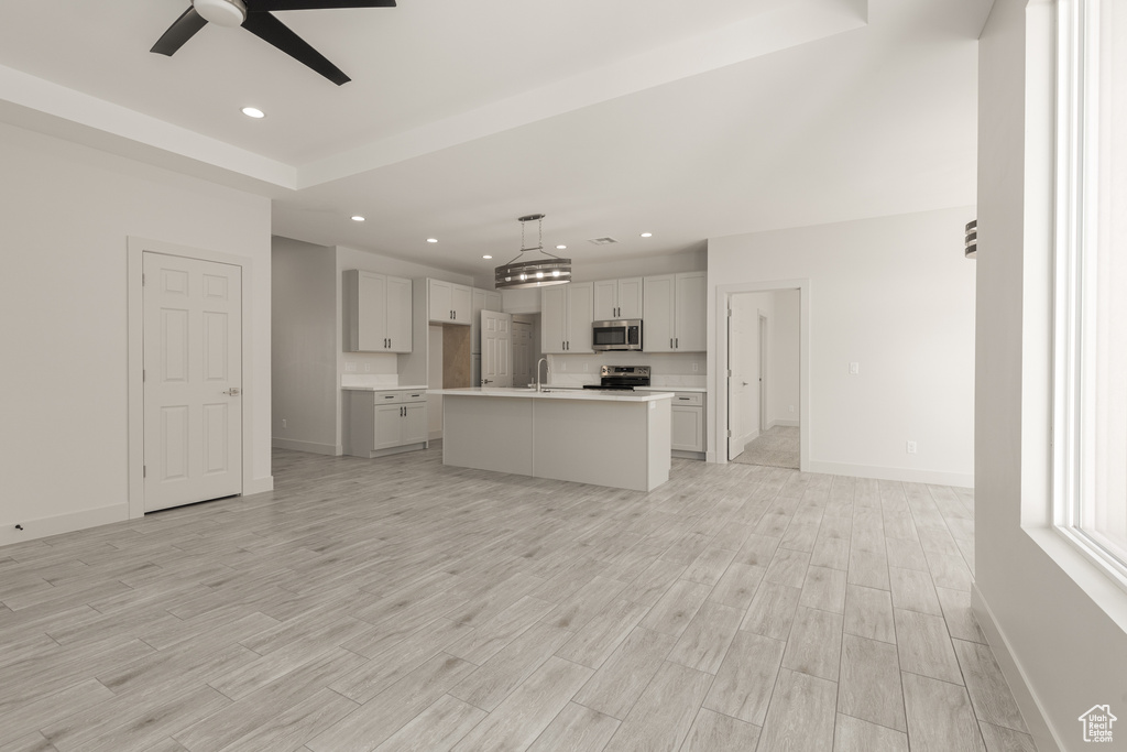 Kitchen featuring appliances with stainless steel finishes, a ceiling fan, open floor plan, recessed lighting, and baseboards