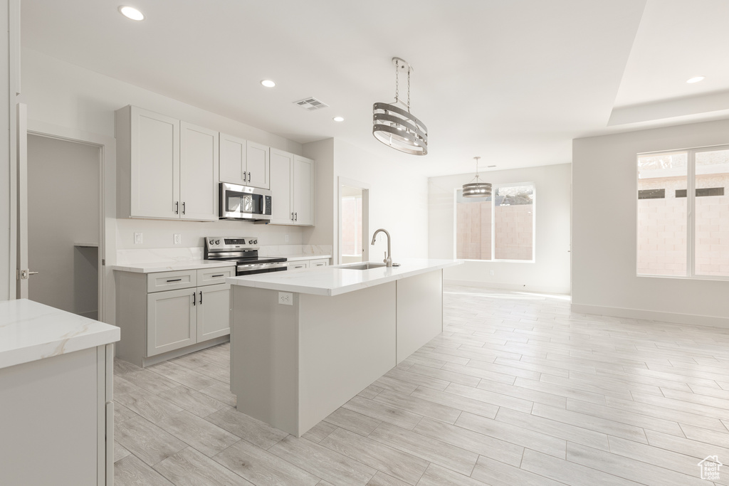 Kitchen with stainless steel appliances, a sink, recessed lighting, a kitchen island with sink, and pendant lighting