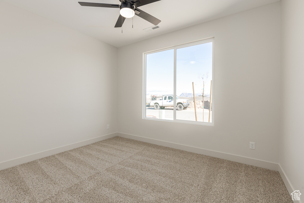 Unfurnished room with light colored carpet, plenty of natural light, baseboards, and a ceiling fan
