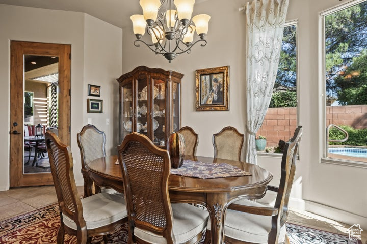 Dining room with a chandelier, light tile patterned floors, and baseboards