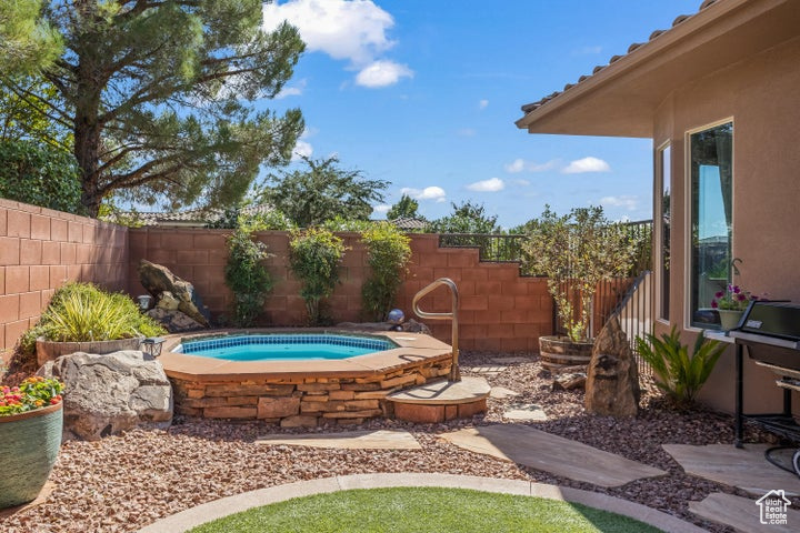 Fenced backyard featuring an in-ground hot tub