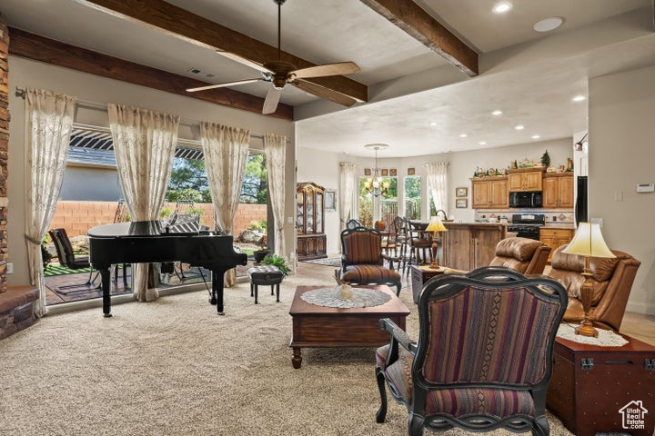 Living area with beamed ceiling, a ceiling fan, plenty of natural light, light carpet, and a chandelier
