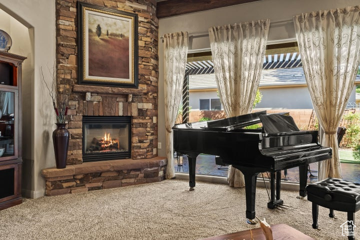 Sitting room with a stone fireplace, carpet floors, and plenty of natural light