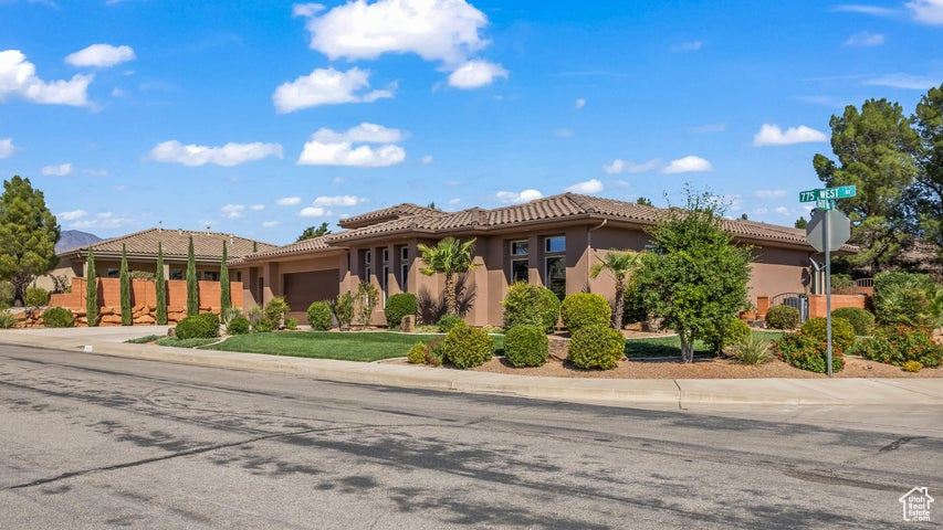 View of front of home with a garage, driveway, a tile roof, and stucco siding