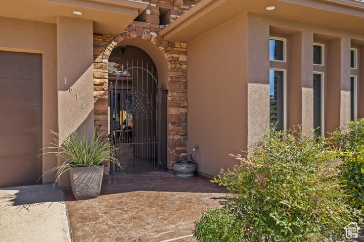 View of exterior entry featuring stone siding, a gate, and stucco siding